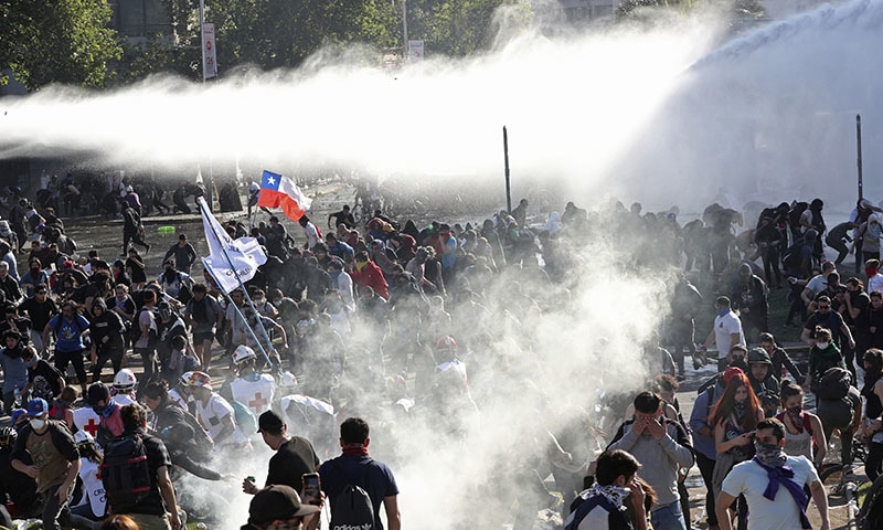 Demonstrators run from police launching water canons and tear gas as a state of emergency remains in effect in Santiago, Chile, Sunday, Oct. 20. — AP