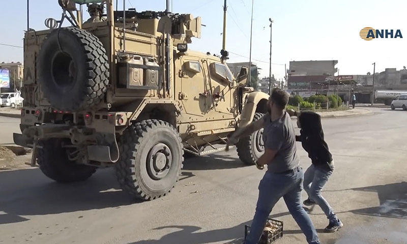 In this frame grab from video provided by Hawar News, ANHA, the Kurdish news agency, residents who are angry over the US withdrawal from Syria hurl potatoes at American military vehicles in the town of Qamishli, northern Syria on Monday. — ANHA via AP