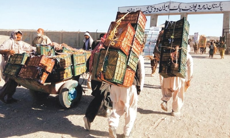 PORTERS at Zero Point in Taftan carrying Iranian apples on their back.—Dawn file photo