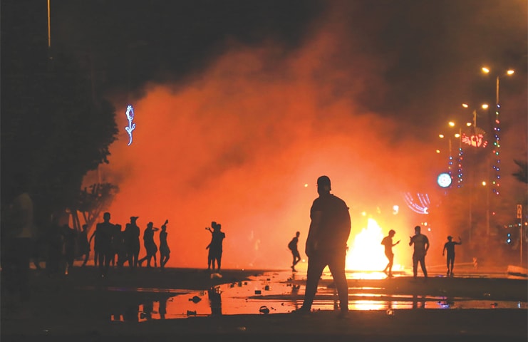 KARBALA: Protesters burn items to block the road as they clash with security forces during an anti-government demonstration on Monday.&mdash;AFP