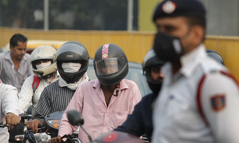 Motorcyclists cover their faces with scarf to save themselves from air pollution as they wait at a crossing in New Delhi, India on Monday. &mdash; AP
