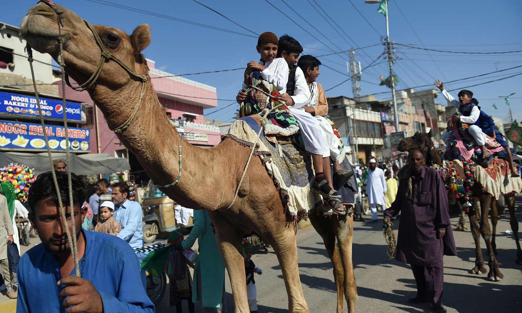 Children sit on camels as they participate in a procession to celebrate the birth of the Holy Prophet (PBUH), in Karachi on Sunday. — AFP