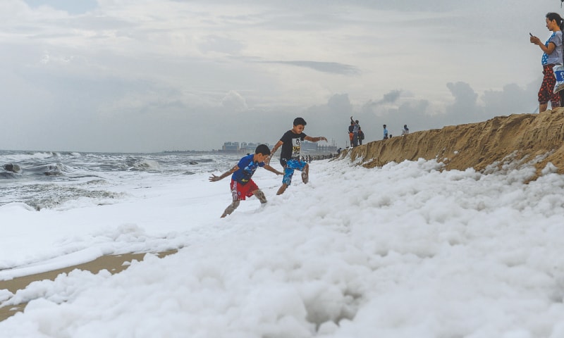 CHENNAI: Children play over foamy discharge on a beach.—AFP