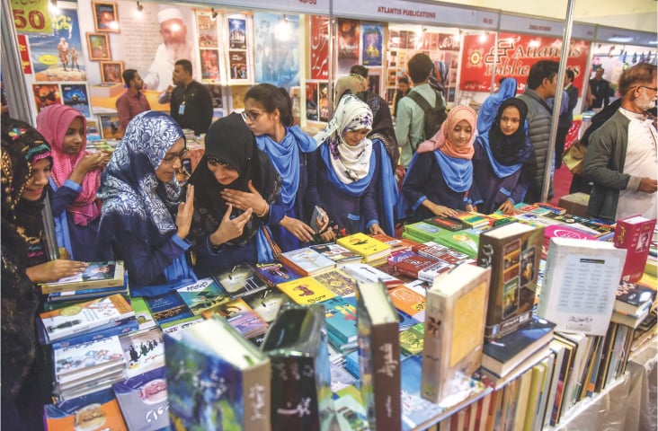 Schoolgirls browse through Urdu titles while (right) schoolboys walk off with newly bought books at the KIBF on Thursday.—White Star