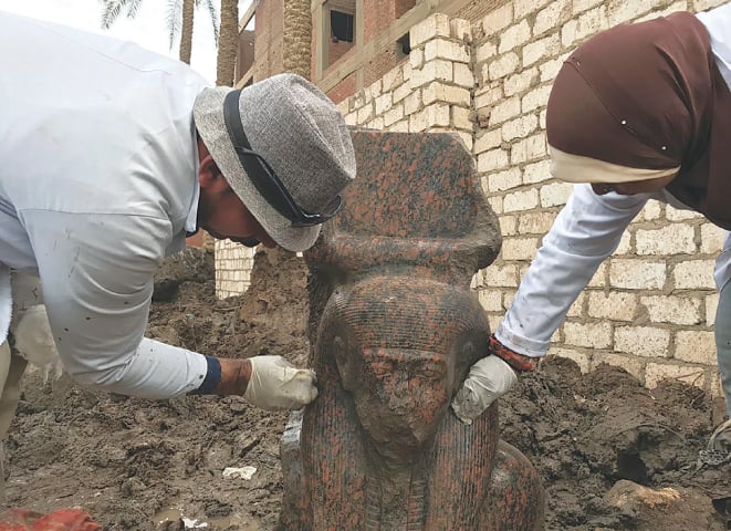 CAIRO: Workers clean a small pink granite statue of Ramses II, near the ancient pyramids of Giza.&mdash;AP