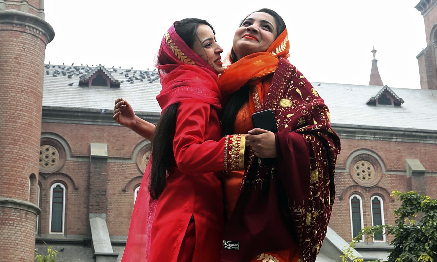 Women greet each other after attending a Christmas Mass at a church in Lahore, Wednesday. &mdash; AP