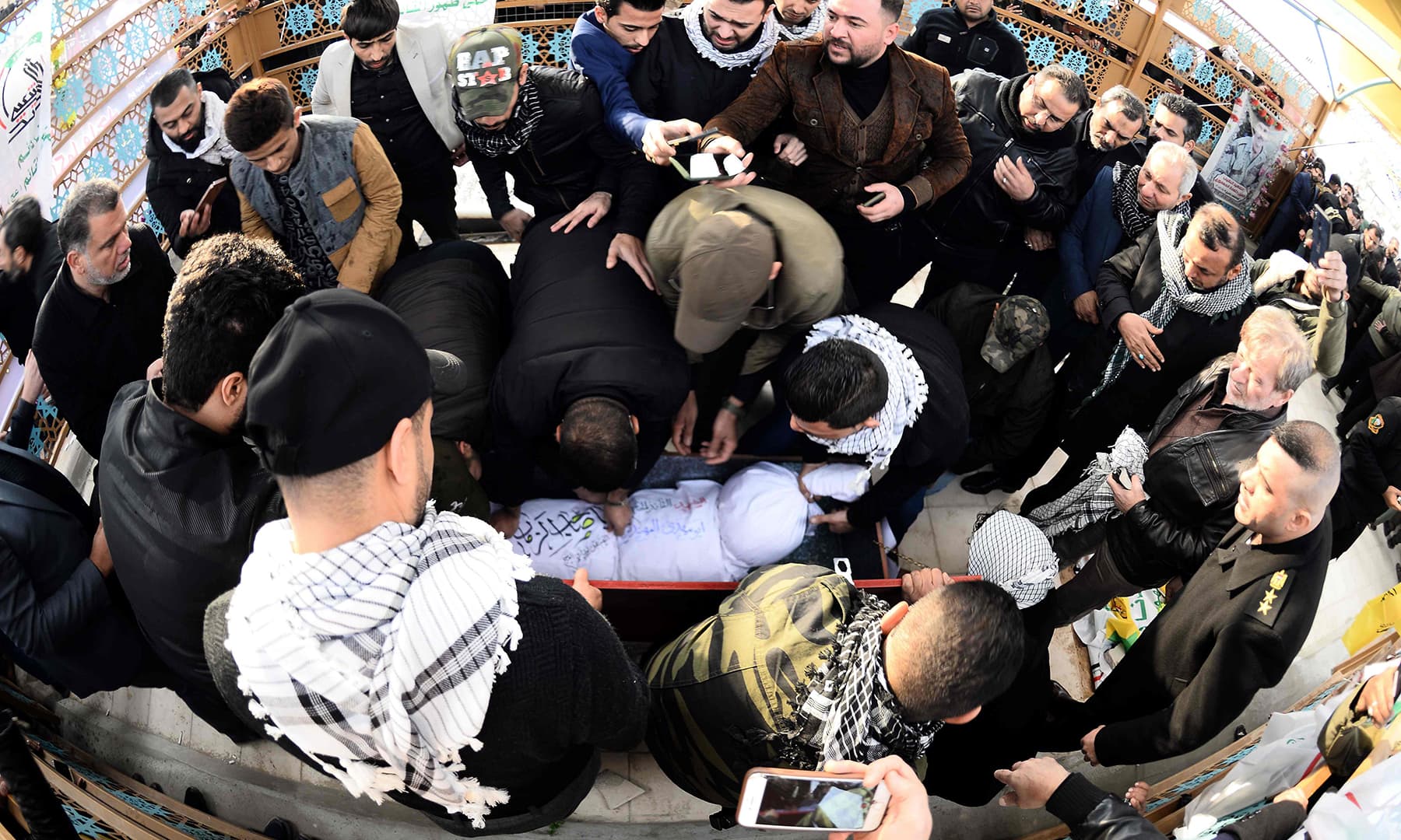 Iraqi mourners, including members of Hashed al-Shaabi paramilitary network, gather around the coffin of the group's slain chief Abu Mahdi al-Muhandis ahead of his burial in the Wadi al-Salam ("Valley of Peace"), in Iraq's holy city of Najaf on Wednesday. — AFP