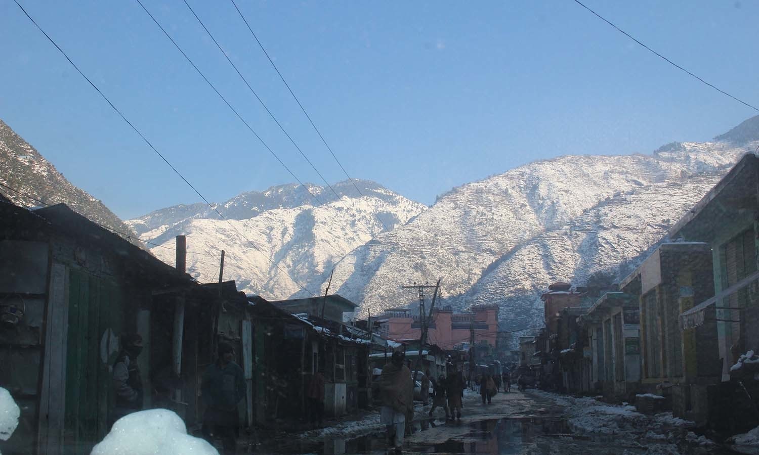 Snow-covered mountains look over the streets of Shangla. — Umar Bacha