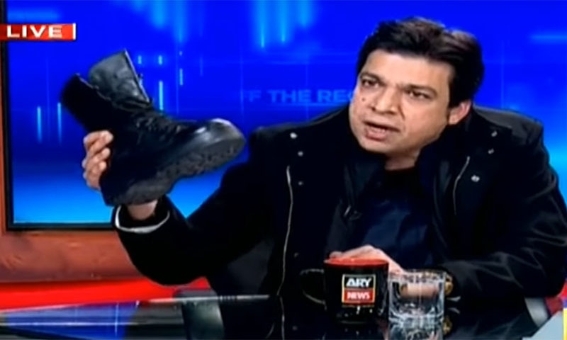 Faisal Vawda, a federal minister belonging to the Pakistan Tehreek-i-Insaf (PTI) brought an army boot to a live TV programme on Tuesday evening to heap scorn on the opposition Pakistan Peoples Party and Pakistan Muslim League-Nawaz for voting in favour of the recently-passed Army Act in parliament. — Screengrab via ARY News YouTube video