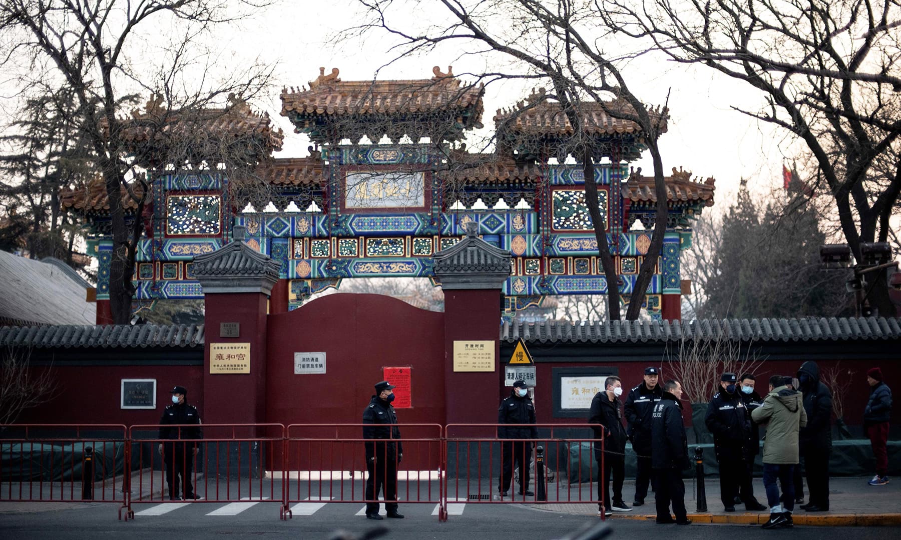 Policemen wearing protective facemasks to help stop the spread of a deadly SARS-like virus which originated in the central city of Wuhan, are seen in front of the closed gate of the Lama Temple in Beijing on January 25, 2020. — AFP