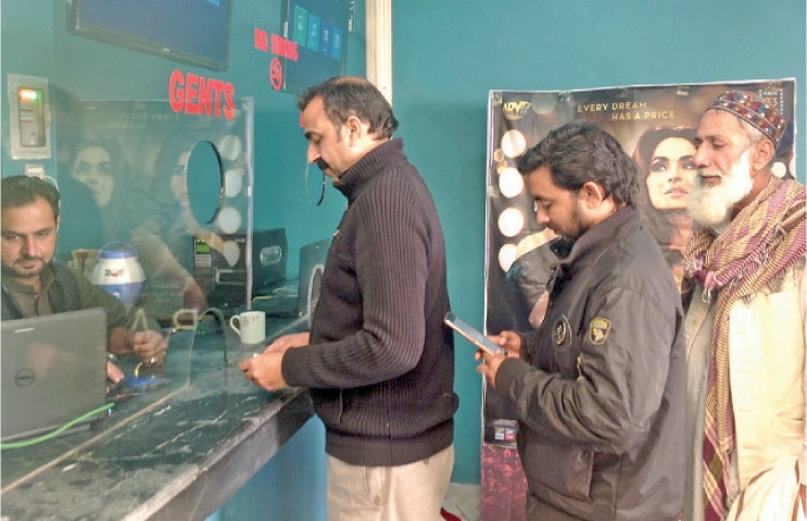 CINE-GOERS buy tickets at the cinema in Peshawar. — Dawn