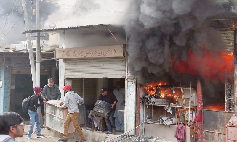 TRADERS try to salvage goods from their shops amid firefighters&rsquo; attempts (below) to douse the inferno in a Malir locality on Tuesday.&mdash;PPI