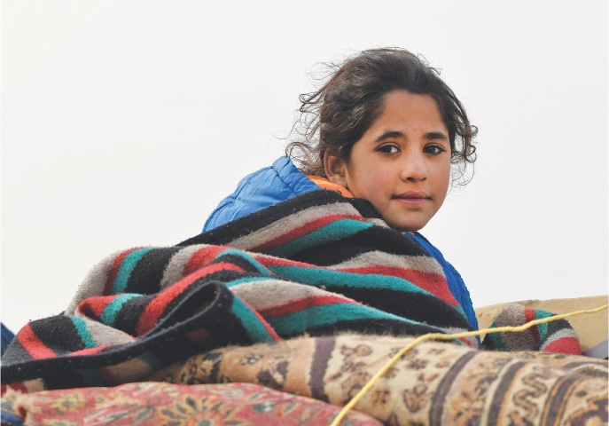 DAYR BALLUT: A displaced Syrian child rides in the back of a truck passing by Dayr Ballut on the way to Afrin and Azaz, near the Turkish border in the rebel-held part of Syria’s Aleppo province.—AFP