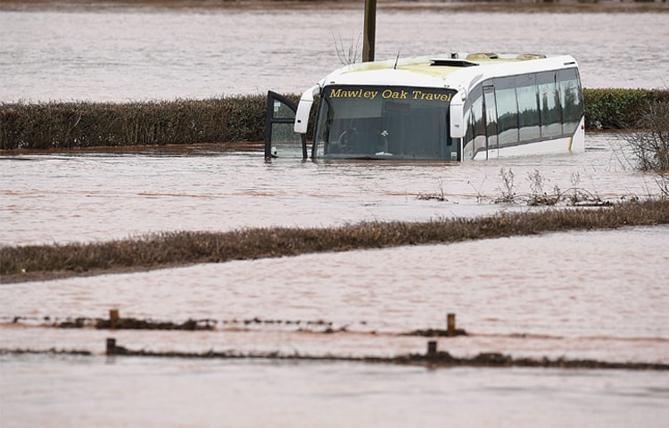 LINDRIDGE: An empty coach sits abandoned after the River Teme burst its banks near this town in western England on Sunday.—AFP