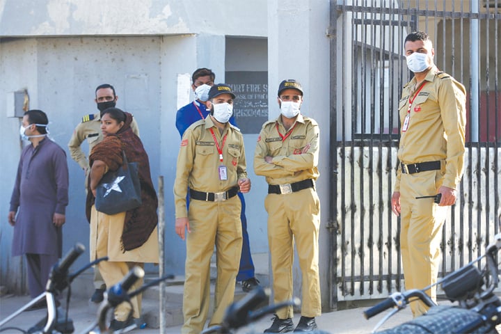 KARACHI: Private guards wearing face masks pictured on Monday outside the hospital where victims of toxic gas leak are being treated.—AP