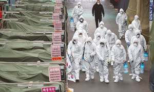 DAEGU (South Korea): Workers wearing protective gear spray disinfectants in a market on Sunday as a precautionary measure against the deadly outbreak of coronavirus.—AFP/File