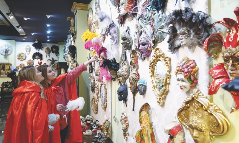 Shkoder (Albania): Visitors look for carnival masks in a salon of the Venice art mask workshop.—AFP Shkoder (Albania): Visitors look for carnival masks in a salon of the Venice art mask workshop.—AFP