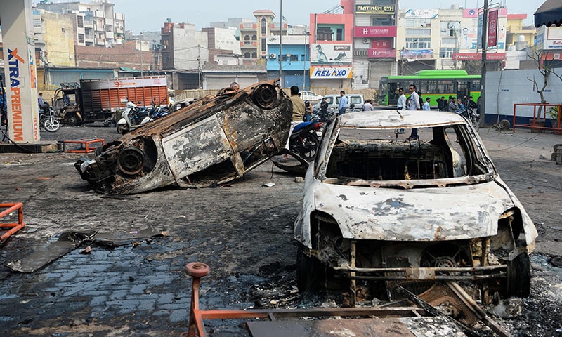 Local residents look at burnt-out vehicles following clashes between people supporting and opposing a contentious amendment to India's citizenship law, in New Delhi on February 26. — AFP