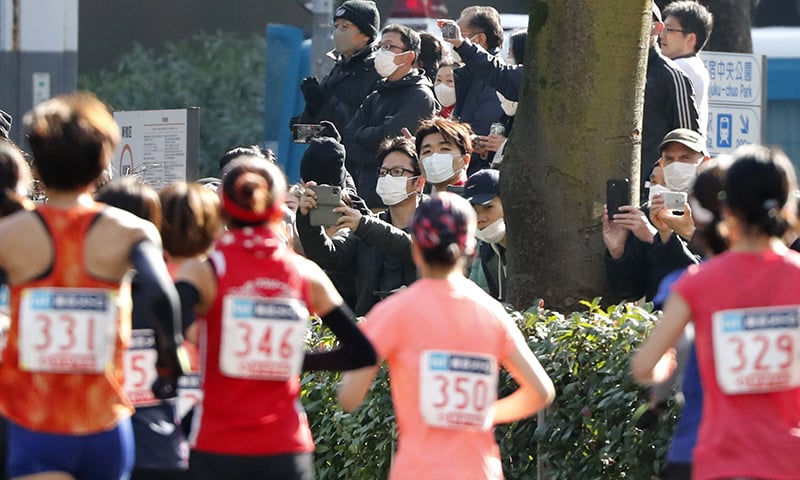 Spectators wearing masks watch the start of the Tokyo Marathon in Tokyo on Sunday. — AP