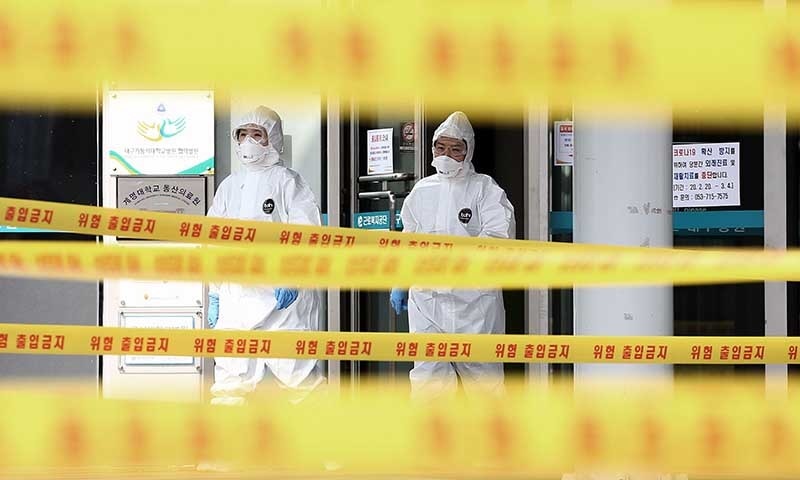 Medical staff members wearing protective gear move inside the yellow control lines at a hospital for patients infected with the COVID-19 coronavirus in Daegu on March 1. &mdash; AFP