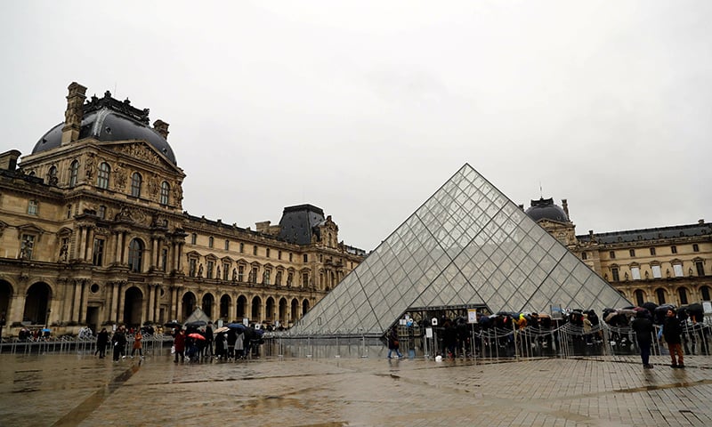 People wait in front of the Louvre Pyramide in Paris on March 1. — AFP