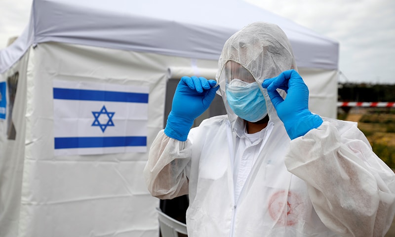 A paramedic adjusts his protective suit as he prepares outside a special polling station set up by Israel's election committee. &mdash; Reuters