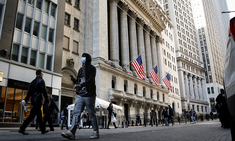 A man wears a mask as he walks near the New York Stock Exchange (NYSE) in the financial district in New York City, US. — Reuters