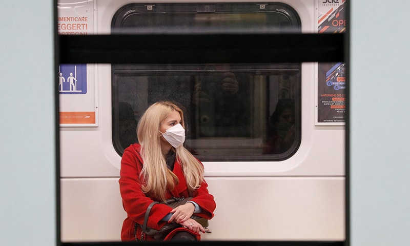 A woman wearing a protective face mask to prevent contracting the coronavirus sits inside a train at a subway station in Milan, Italy, March 3. &mdash; Reuters