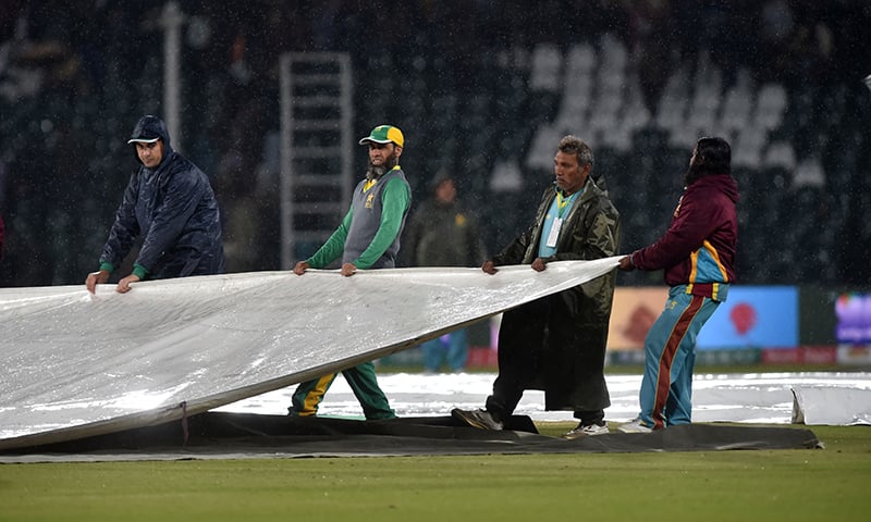 Ground staff members cover the pitch during rain showers during the Pakistan Super League (PSL) T20 cricket match between Karachi Kings and Multan Sultans at the Gaddafi Cricket Stadium in Lahore on March 6. — AFP