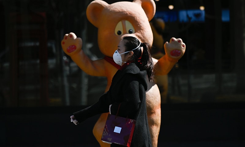 A woman wearing a face mask walks past a toy mall in Beijing on March 7. &mdash; AFP
