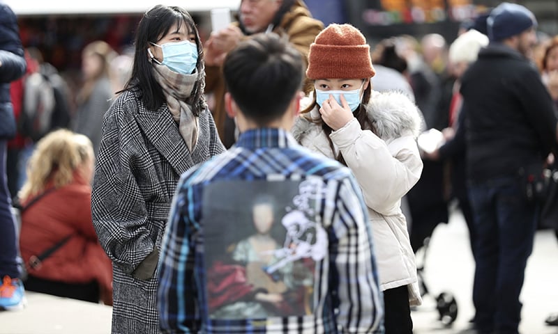 People wearing face masks stand in Piccadilly Circus, London on Saturday. — AP