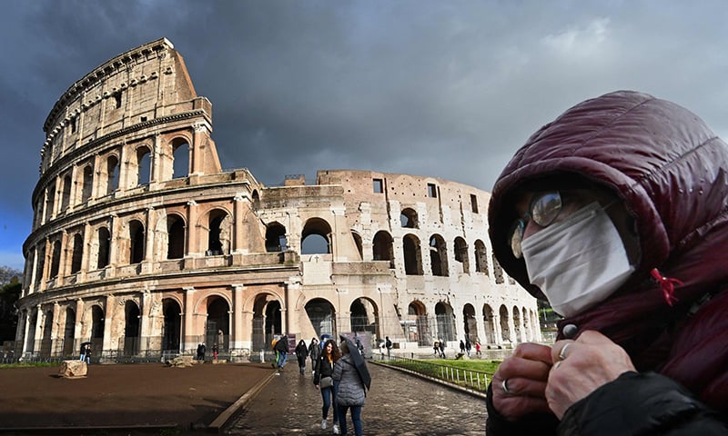 A man wearing a protective mask passes by the Coliseum in Rome on March 7 amid fear of Covid-19 epidemic. — AFP