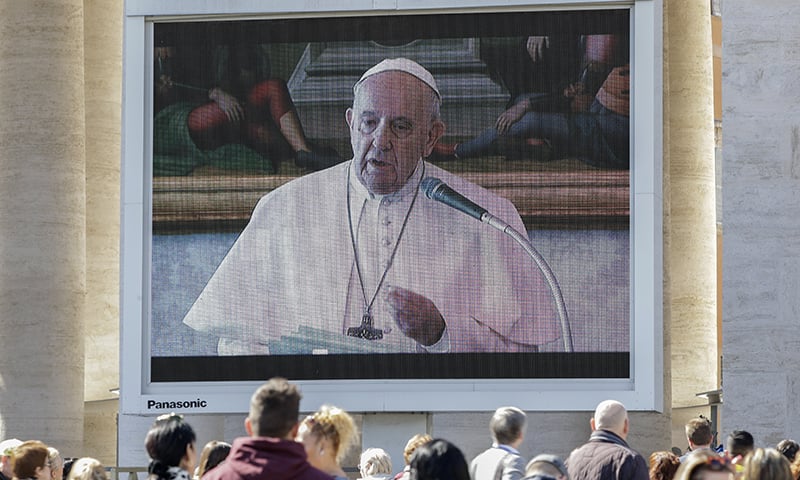 People watch Pope Francis deliver the Angelus prayer on a giant screen in Saint Peter's Square. &mdash; AP