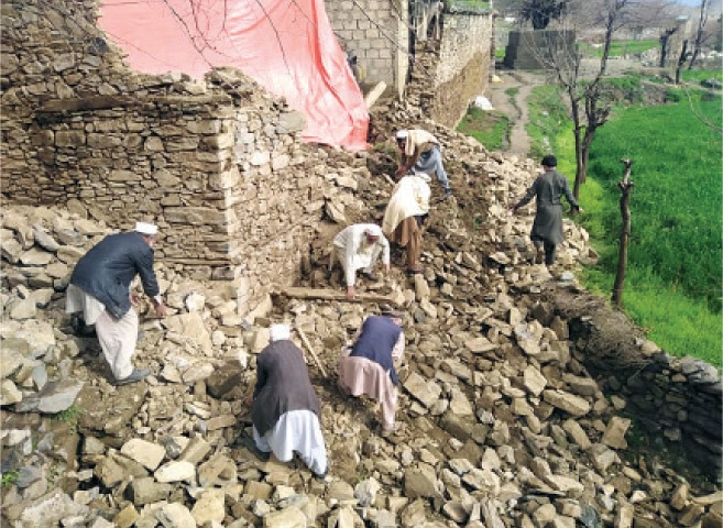 Locals remove the rubble after roof of a house collapsed in Bajaur on Sunday. — Dawn