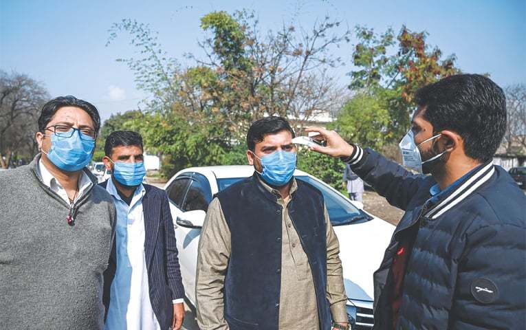 An official of a Pakistan-based Chinese company uses a thermo gun to check the temperature of the firm&rsquo;s drivers on Thursday. The authorities have issued instructions to take preventive measures against the coronavirus. &mdash; AFP