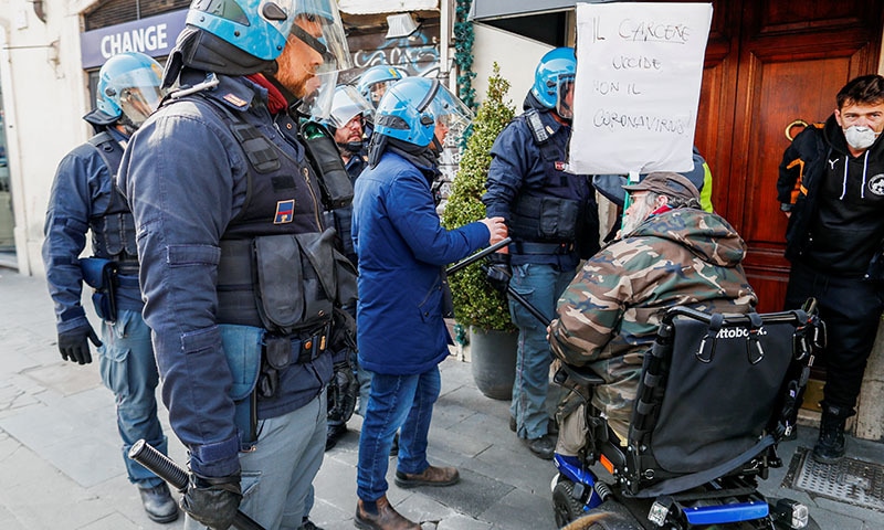 A man holds a banner saying "Prison kills not the coronavirus" near the Ministry of Justice building after holding a demonstration over family visits to prisons being suspended due to coronavirus fears, causing riots in prisons across Italy, in Rome, Italy March 10, 2020. REUTERS/Yara Nardi