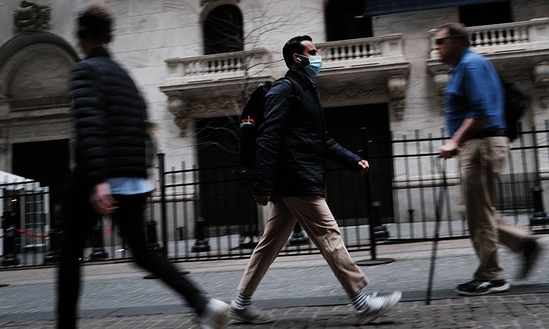 A man in a medical mask walks by the New York Stock Exchange on March 10, 2020 in New York City. &mdash; AFP