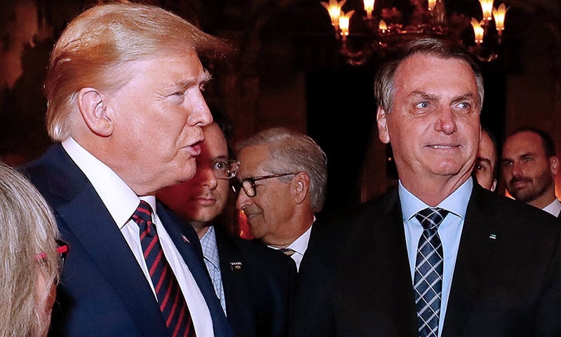 Handout picture released by the Brazilian Presidency on March 12 showing US President Donald Trump (L), Brazilian President Jair Bolsonaro (R) and his press advisor Fabio Wajngarten (2-L, behind Trump) during a dinner in Mar a Lago, Florida, United States, on March 7. &mdash; AFP photo/ Brazil's Presidency/ Alan Santos