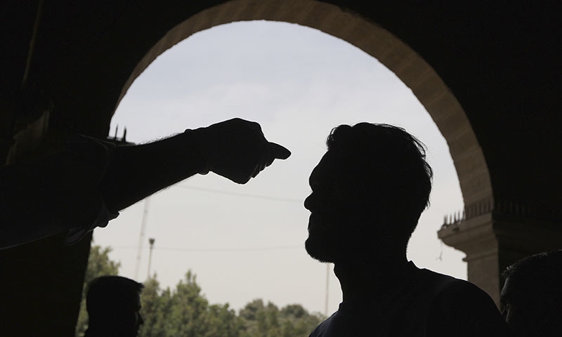A health official checks the body temperature of a passenger at a railway station in Karachi, Pakistan on March 15, 2020. Authorities have stepped up efforts to contain the spread of the virus. — AP
