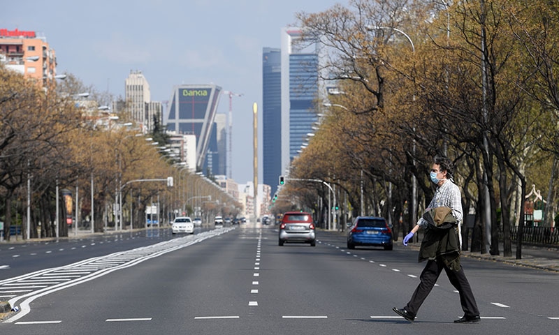 A man wearing a face mask and gloves crosses the usually busy La Castellana avenue in Madrid on March 15, 2020. France and Spain are the latest European nations to severely curtail people's movements as countries across the Americas and Asia impose travel restrictions in a widening crisis over coronavirus. — AFP