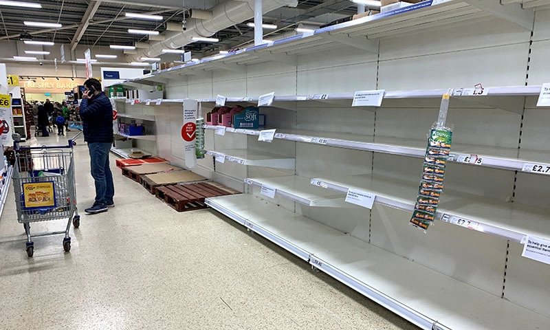 A man talks on his phone as he stands at an empty toilet roll aisle in a Tesco supermarket in Manchester, Britain, on March 14, 2020. — Reuters