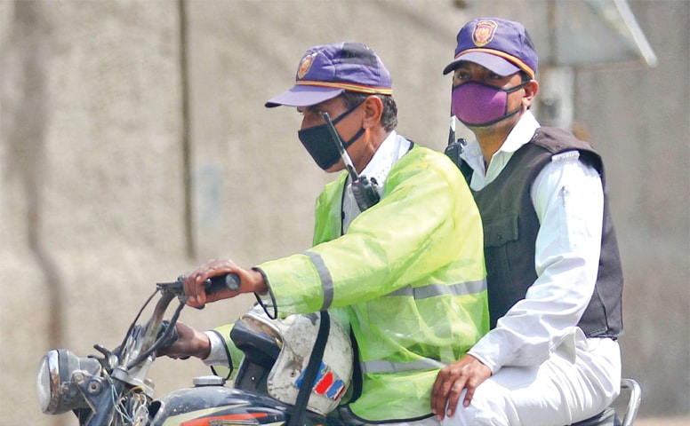 TWO traffic policemen ride a motorcycle wearing face masks on Monday.—INP