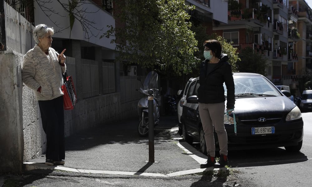 Enza Garzia, 79, left, talks at a distance with Paola Albano, in central Rome on March 11, 2020. — AP