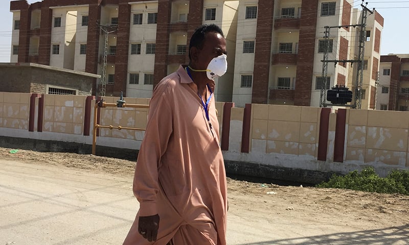 A man wears a protective mask following an outbreak of the coronavirus as he walks in front of buildings, declared by the government as quarantine for the suspected pilgrims, who crossed Taftan border post with Iran, in Sukkur on Mrach 18. — Reuters