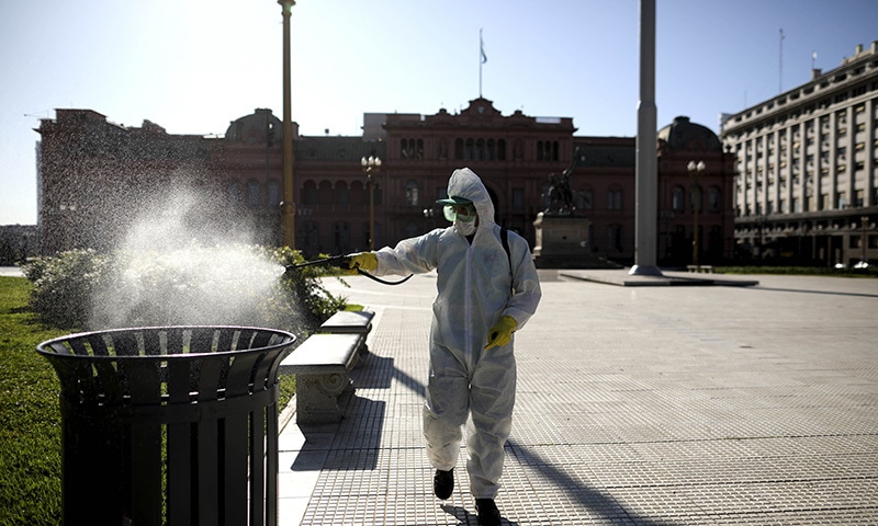 A man sprays bleach at Plaza de Mayo in Buenos Aires, Argentina on Friday, March 20, 2020. Argentina's government imposed a countrywide lockdown to contain the spread of the coronavirus. &mdash;AP