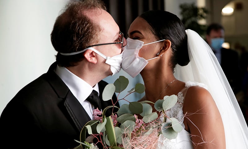 Newlyweds Diego Fernandes, 46 and Deni Salgado, 30, kiss through protective face masks at a wedding ceremony with only witnesses and no guests in Naples on March 20. — Reuters
