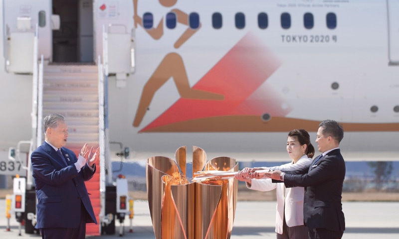 HIGASHIMATUSHIMA: Three-time Olympic gold medallists Tadahiro Nomura (R) and Saori Yoshida light the torch as Tokyo 2020 Olympics chief Yoshiro Mori looks on during the Olympic Flame Arrival Ceremony at the Matsushima Base on Friday.&mdash;AP