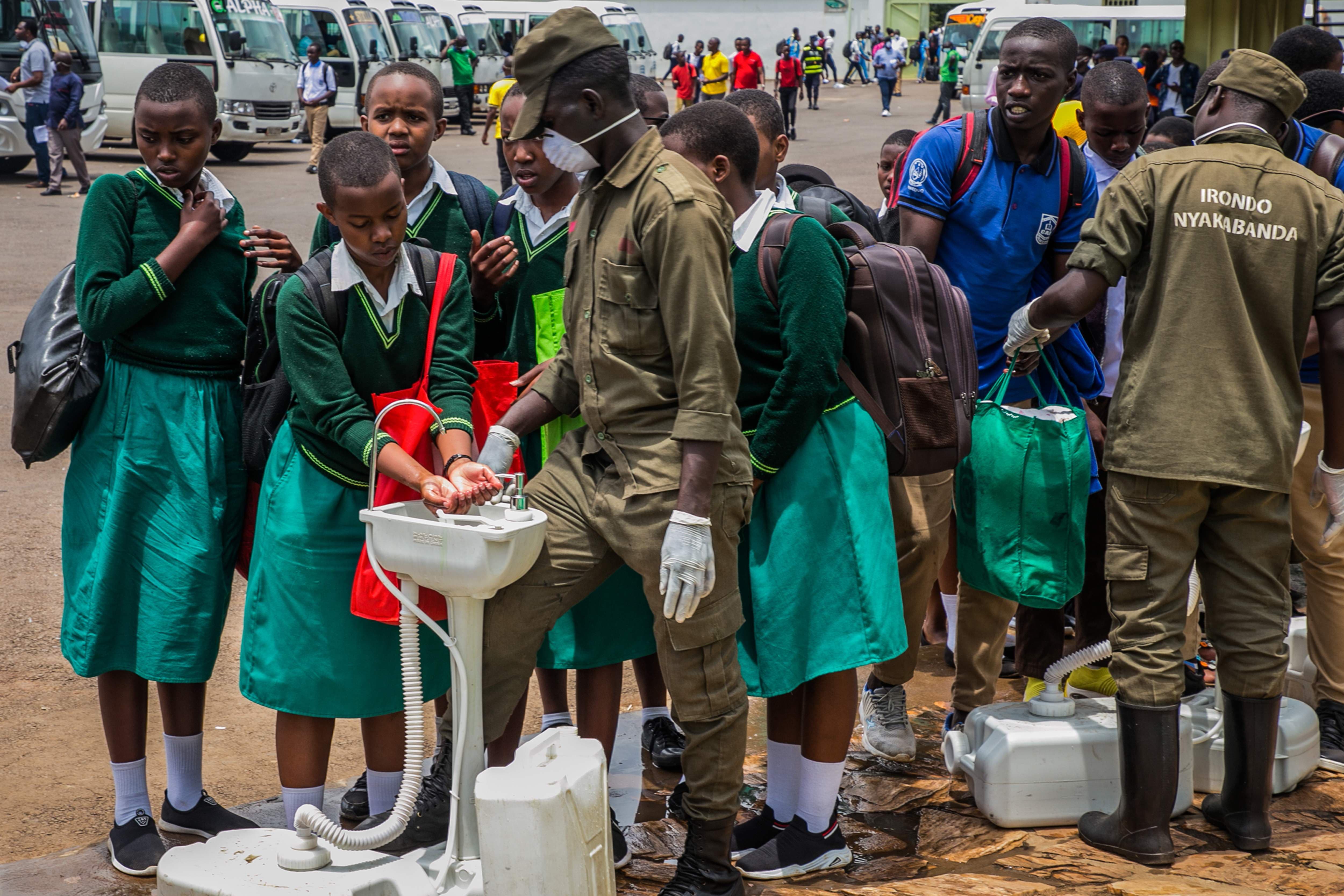 Rwandan students wash their hands at temporary hand washing points before they are sent back home from boarding schools | AFP