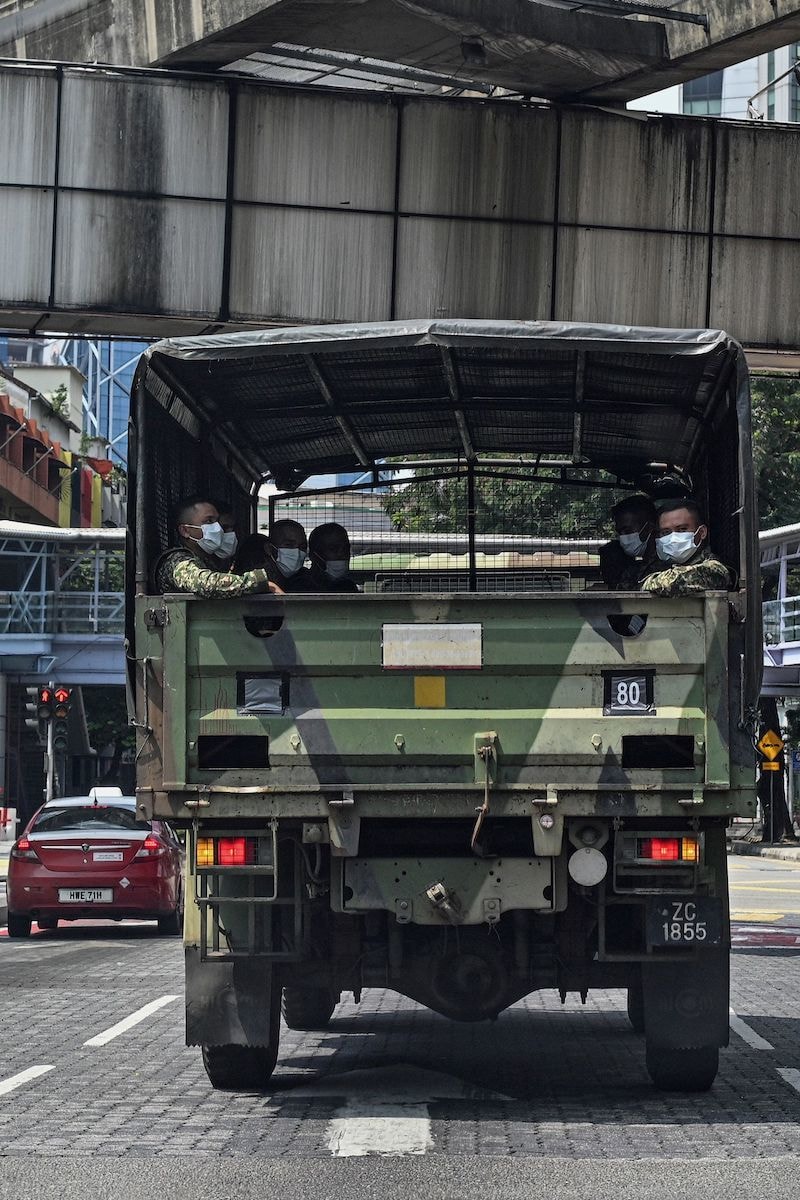 Soldiers wearing face masks look out from an army truck during the control of movement in Kuala Lumpur on March 22, 2020, amid fears over the spread of the COVID-19 novel coronavirus. &mdash; AFP