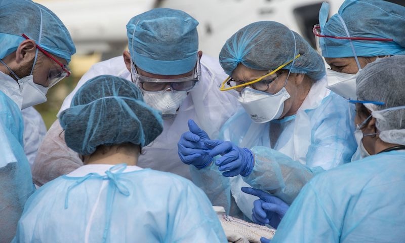 Medical staff are bent over a patient being evacuated on a trolley to a medical helicopter at The Emile Muller Hospital in Mulhouse, eastern France on March 22, as patients are evacuated to another hospital facility, on the sixth day of a strict lockdown in France to stop the spread of COVID-19. — AFP
